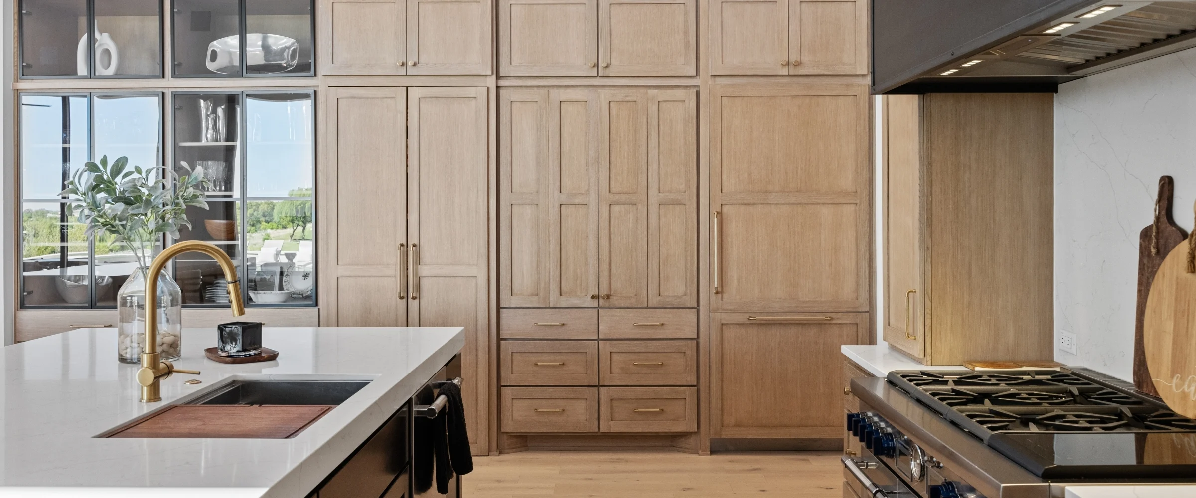 Kitchen with white oak cabinetry and a brass faucet