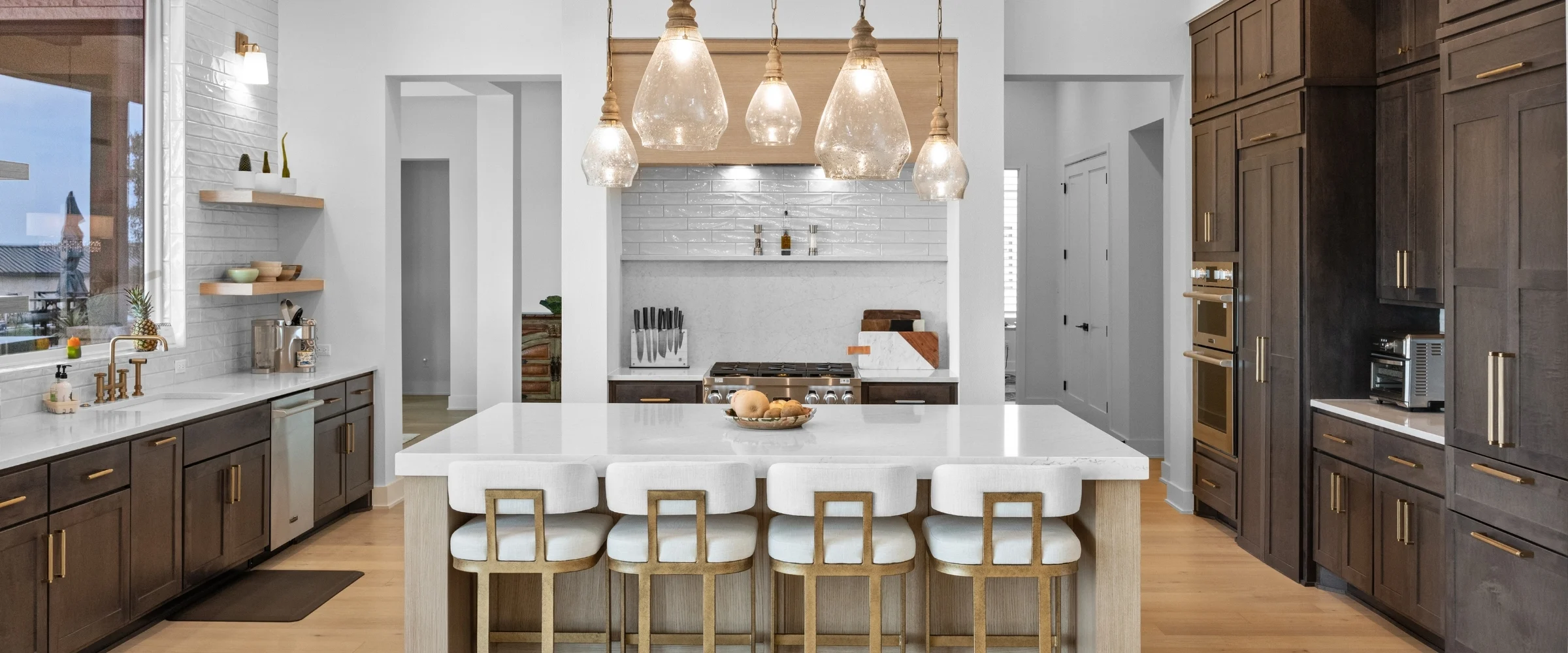 Kitchen with glass pendant lights over a white island and bar stools