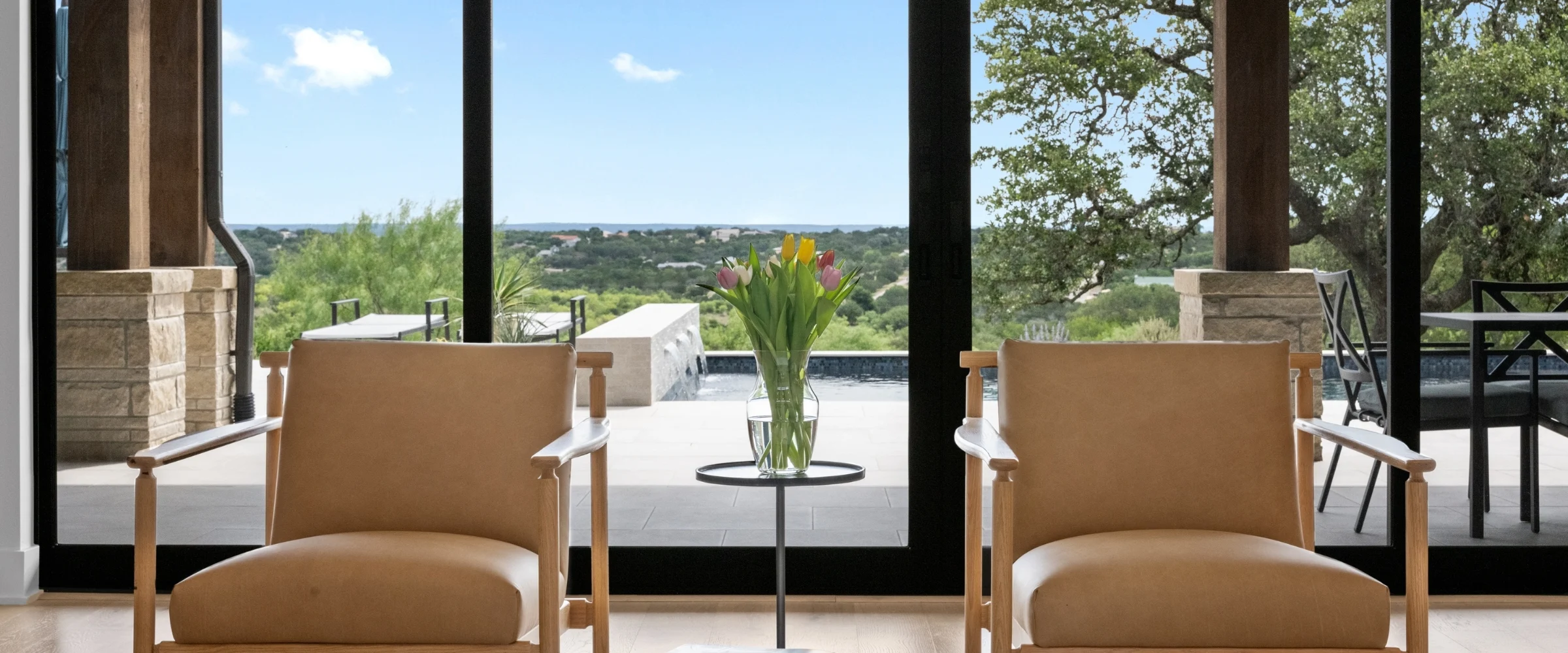 Two leather chairs facing floor-to-ceiling windows and a Hill Country view