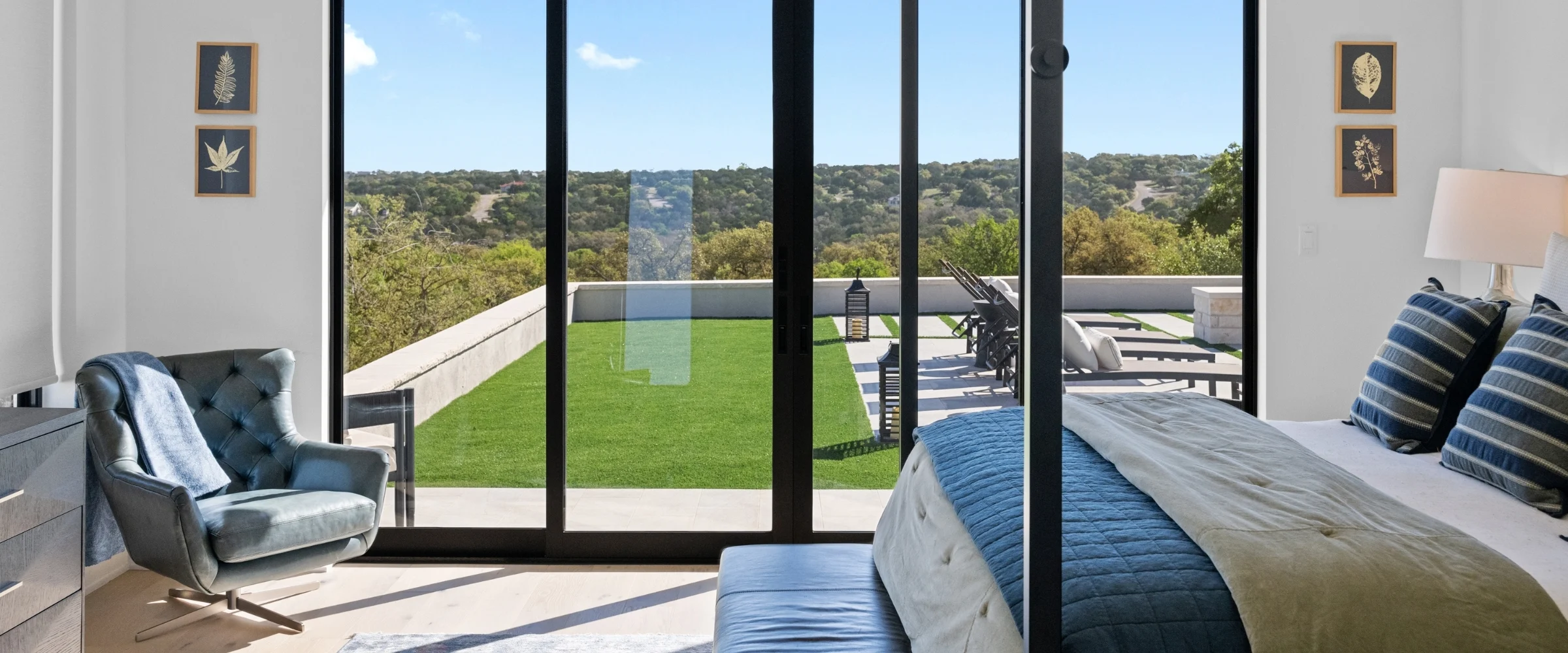 Bedroom with floor-to-ceiling glass opening onto a lawn terrace