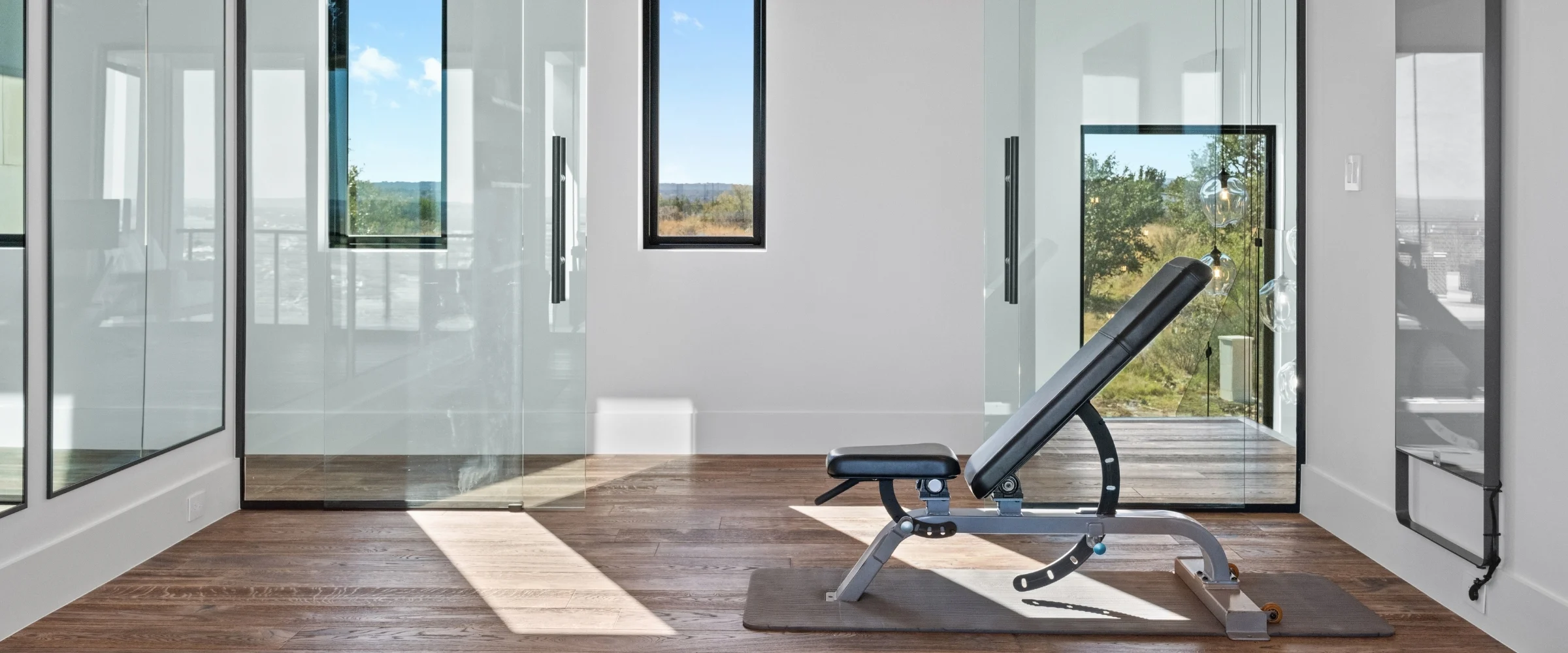 Home gym with glass walls and wide-plank wood floors